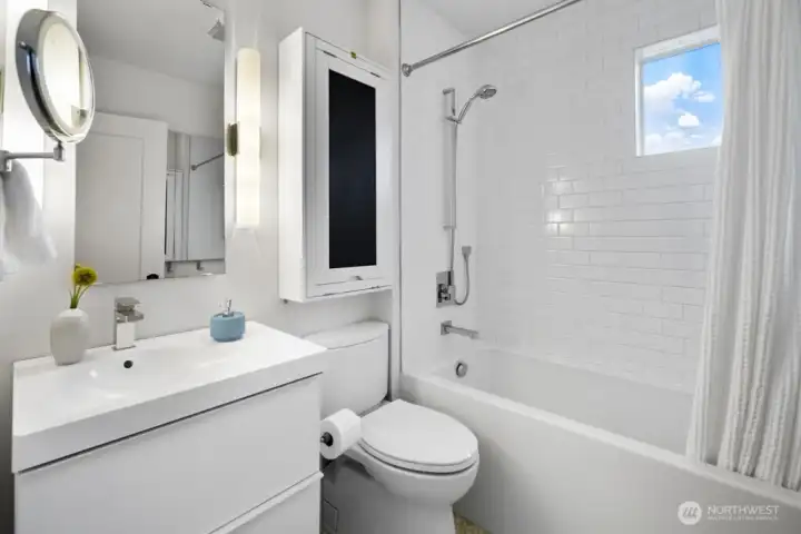 Bright full bath with subway-tile surround, soaking tub, and stowaway vanity table.
