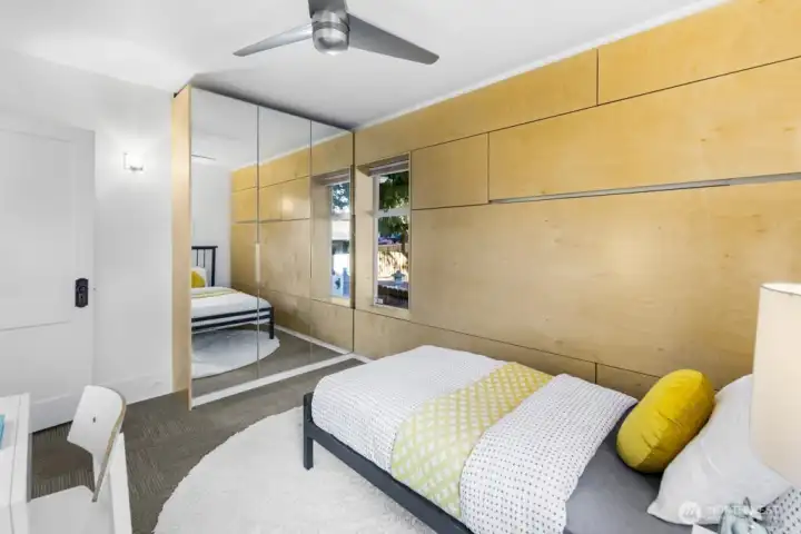 Second bedroom showcases a mirrored closet and paneled feature wall—light, storage, and style.