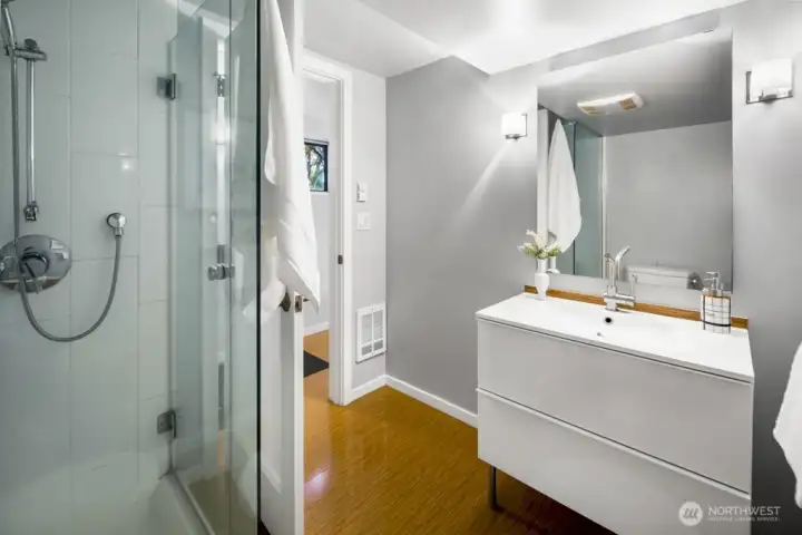 Fresh bathroom with glass-enclosed shower, modern vanity, and clean, neutral finishes.