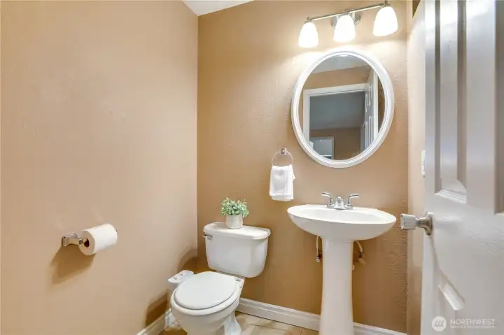 A bright, inviting half bath with a pedestal sink adds charm and convenience.