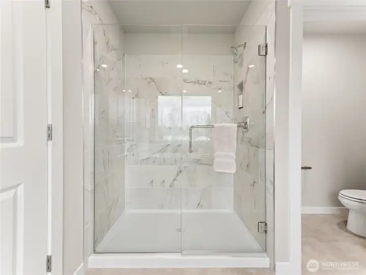 Large walk-in shower in the primary bathroom. Photo is representational. Actual home is under construction and finishes and paint colors may vary. See site agent for details....
