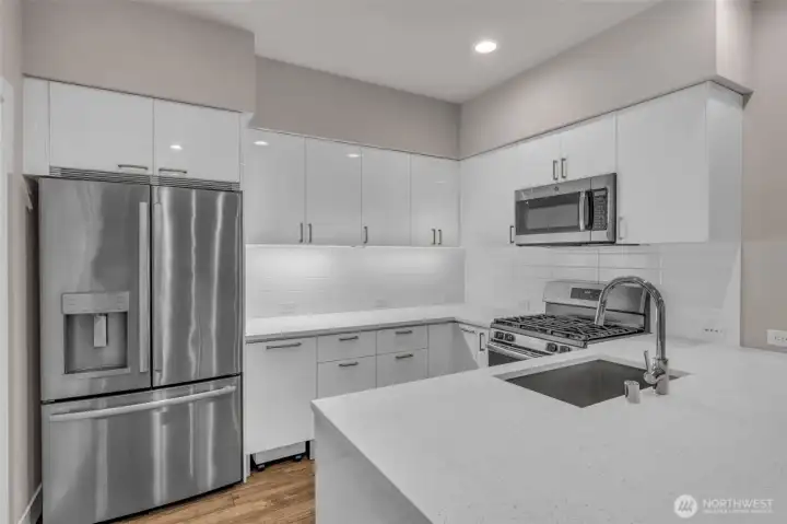 Kitchen with quartz countertops, stainless steel appliances, and custom cabinet organizers