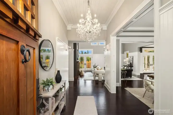 Grand entrance through a custom walnut door and statement chandeliers.