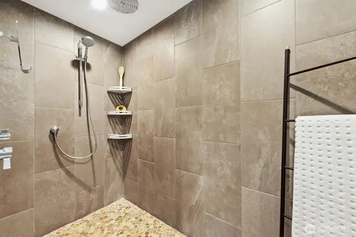 Expansive spa like shower with travertine tile