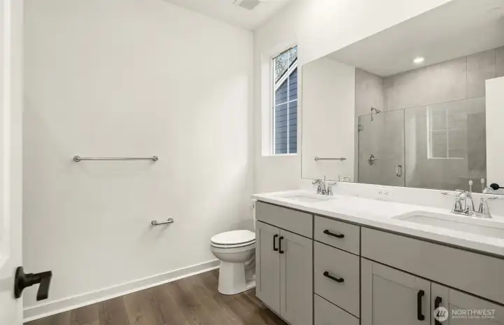 Primary bath with double sink vanity and large walk-in shower with bench.