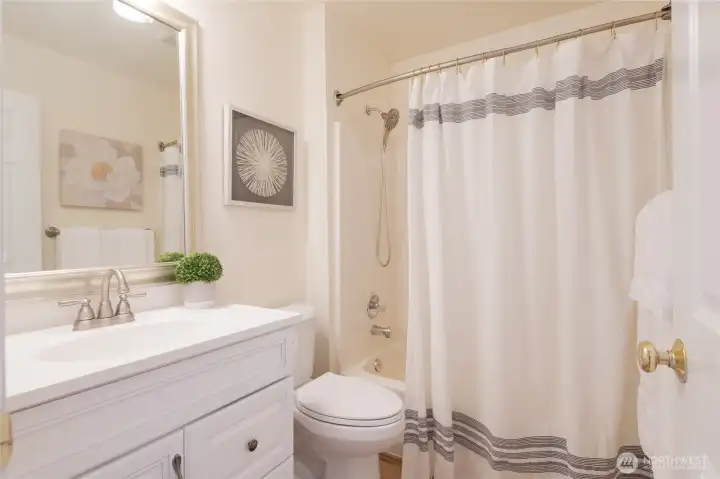 Upstairs Full bath with crisp, white cabinetry and updated fixtures and LVP flooring.