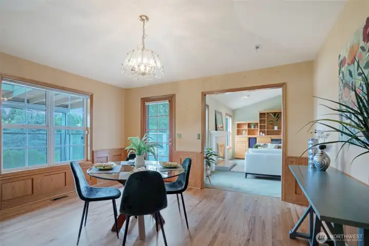 The formal dining room seamlessly connects to the formal living room, creating an effortless flow for entertaining. French doors provide access to the outdoor living space, while expansive windows bring in natural light and offer views of the lush landscape and glimmers of the lake.