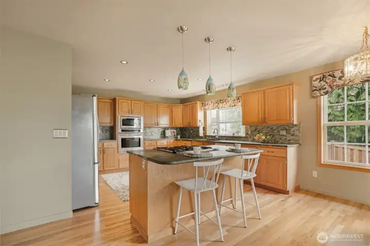 A true cook’s delight—this gourmet kitchen blends style and function with striking solid-surface countertops, rich custom tile backsplash, and expansive cabinetry that offers storage for everything from spices to stand mixers. The oversized center island with gas cooktop and breakfast bar is perfect for prepping meals or gathering with guests over morning coffee.