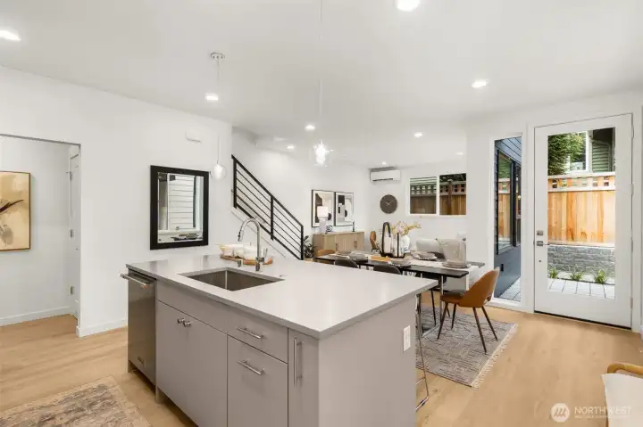 Floor-to-ceiling windows bathe the living room in sunlight, highlighting the airy proportions and tall ceilings.