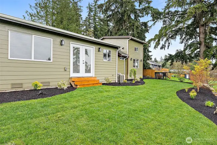 French doors from the primary bedroom lead out to the back lawn and views to the valley