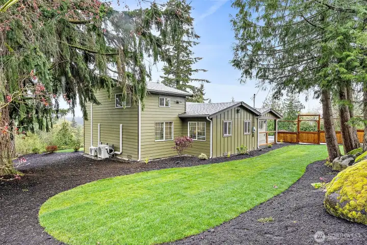 Front of the house is fenced on 3 sides to provide some privacy from the lane.  Huge boulders left by the last glaciers are used as a focal point for this lovely nw garden garden area