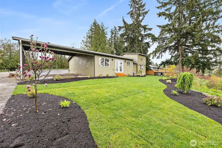 View from the back yard into the l  large attached 2 car carport.  Not pictured is Parking for SO many vehicles here... space for RV or a future garage/shop.