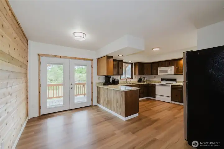 The spacious kitchen is ideal for gathering, while the dining room features warm cedar-lined walls and French doors leading to a covered deck. The spacious kitchen is ideal for gathering, while the dining room features warm cedar-lined walls and French doors leading to a covered deck.