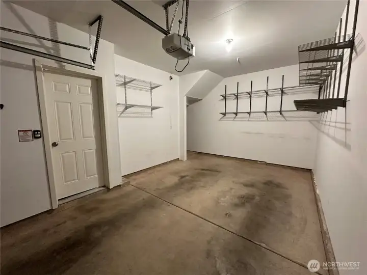 One car garage also has lots of shelves and more storage space in the far left corner.