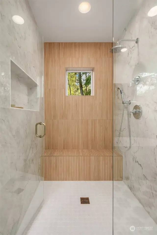 Walk-in shower with frameless glass enclosure, niche and built-in bench.