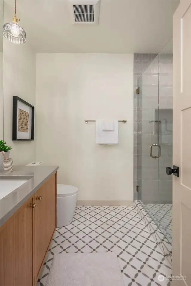 Upper level guest bedrooms ensuite features walk-in shower with curb-less glass enclosure.