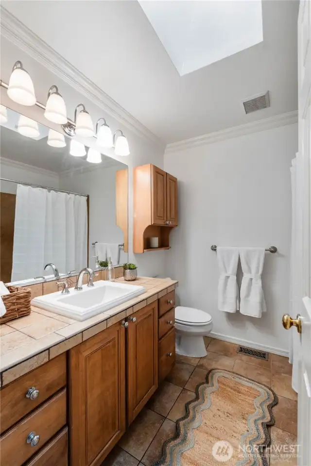 Main full bathroom has a skylight to fill this space with natural light. Beautiful tile floors and counters.
