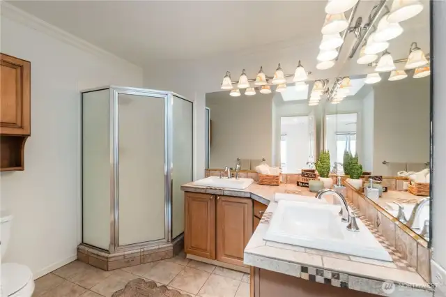 Private primary suite bathroom offers dual vanities and a walk-in shower.