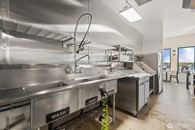 One of the sink stations has 3 sinks and commercial sprayer.