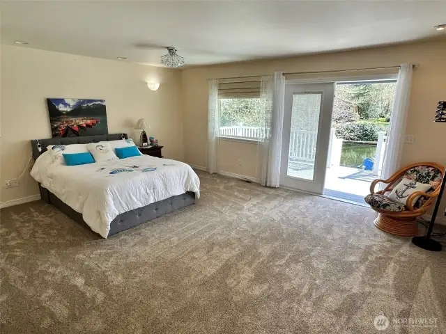 Extra large primary bedroom with french doors leading out to expansive deck with canal views
