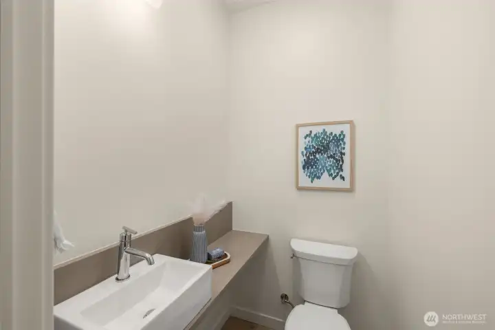 A thoughtfully designed powder room with sleek finishes, offering a blend of functionality and modern style. Photos of home with similar layout, finishes & fixtures.