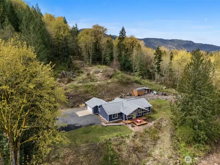 Perched on the upper portion of the property with territory mountain views, privacy, circular drive, RV hookups, fruit trees, & mature forest.
