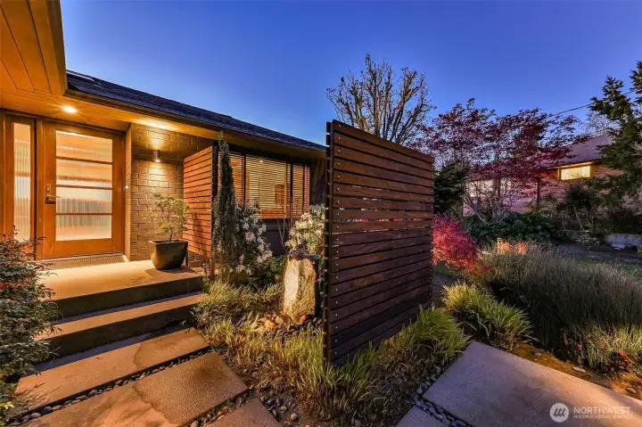 Enter through the custom yard with water feature, custom ipe wall and mature plantings