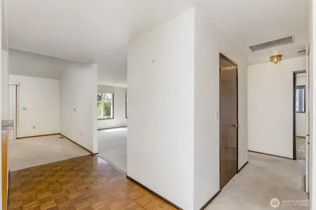 Standing in the entry with the dining room to the left, the livingroom ahead and the hall way to the bedrooms on the right.