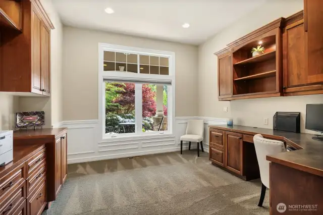 The office is located in the primary bedroom wing next to the bedroom and offers custom built in cabinetry and French door entrance