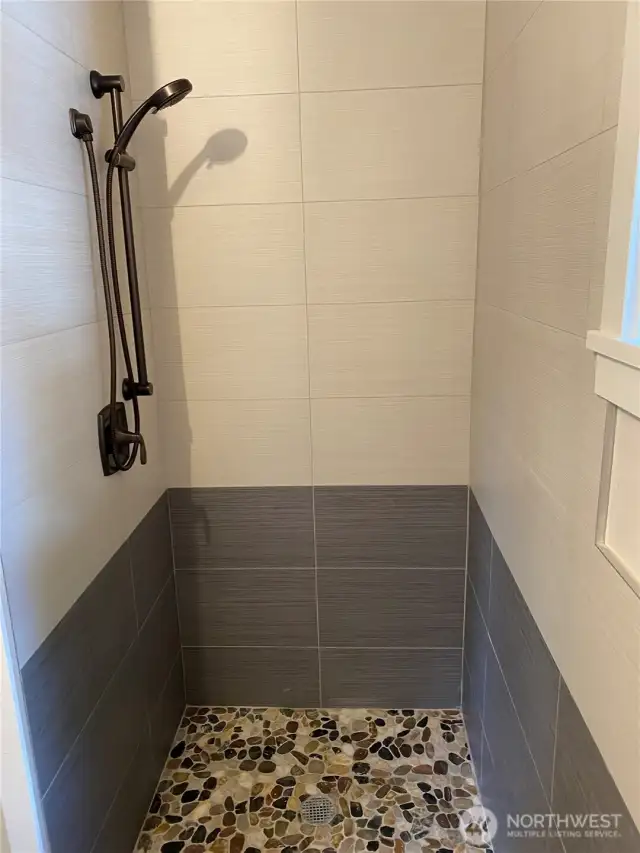 DADU Shower with Ceramic Tile Surround and Ceramic Pebbles Tile Base.