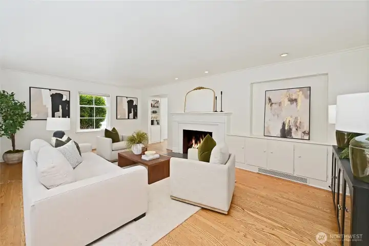 To the left of the front door is the gracious living room with gleaming hardwood floors and a wood burning fireplace