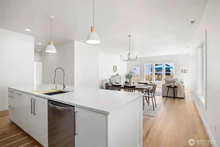 Looking across the large island with the eating bar and deep sink toward the dining area and living room. There is a lovely coffee or prep area below the window to the right of the island.