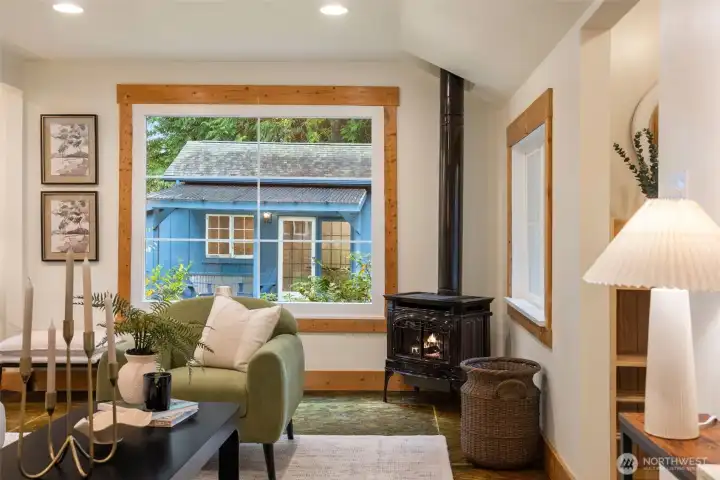 Main home cozy living room w/ gas fireplace. View of the studio through the large picture window.