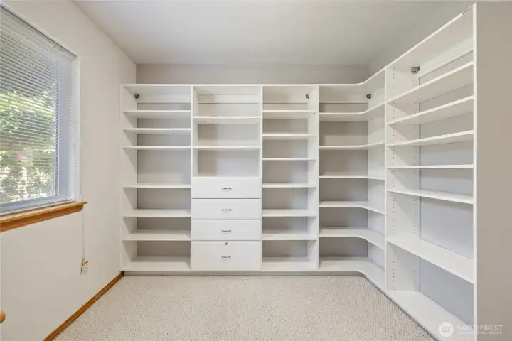 One bedroom currently being used as an office featuring crisp white built-ins for organized storage.