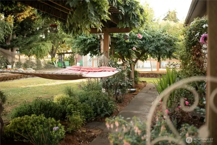 The landscape includes a culinary herb garden, white table grapes on an arbor, and a productive berry patch with raspberries, strawberries, and blueberries. An established orchard features multiple apple varieties, Italian prunes, Asian plum, pear, cherry, and wild field apples. Raised garden beds sit within a low-maintenance English-style garden designed to support pollinators, alongside a lavender garden with English, Spanish, and French varieties.