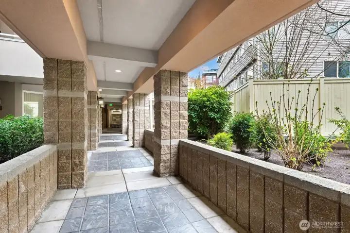 This view is looking down the walkway from unit 207. Exterior covered walkway with lovely gardens on both sides. Refreshing walk to and from your unit. The elevator is right as you turn up to the exit gates.
