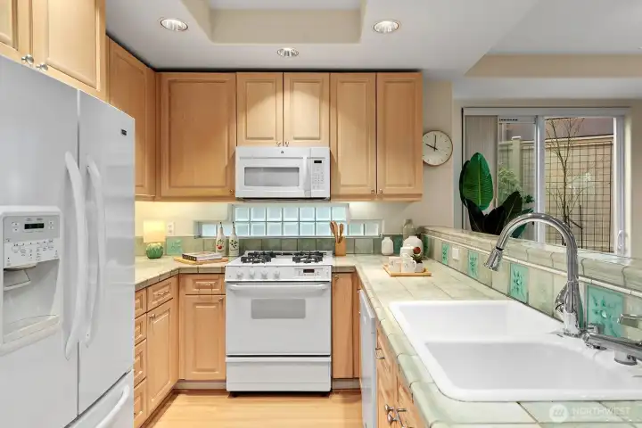 Direct view of the open kitchen. There is a pantry to the left of the refrigerator. There are 2 lazy Susan's one on each side of the stove. Look at all the light coming in from the patio slider.