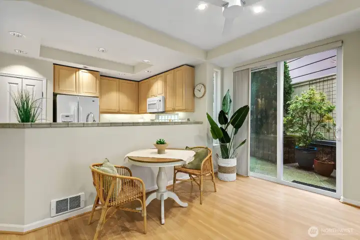 View from the living room to the open kitchen, dining area and you can see the slider leading out to the 2nd patio. This patio extends to the left the length of the unit. You can see the garden and flower pots that can fill this area.