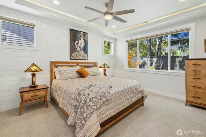 Primary bedroom with lighted coffer ceiling overlooks waterfall and private back yard