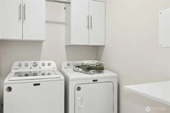 Convenient laundry room with folding table is also the tech hub for the home, with wiring and router for modern living.