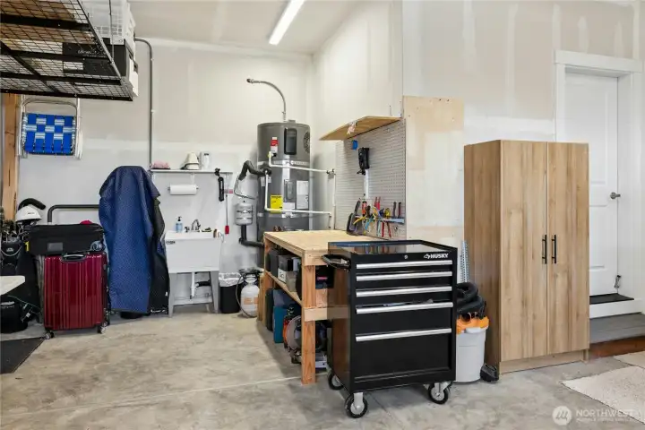 Two car garage with shop space, work bench & storage. Deep utility sink, pre-wired for EV charging plug.
