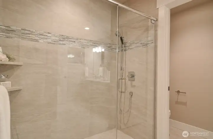 Large tiled shower with glass door in the primary bath. Large tiled shower with glass door in the primary bath.