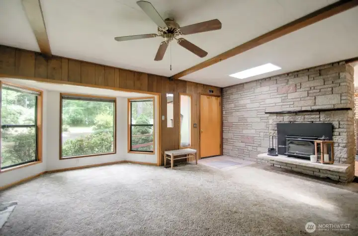 A wider view of the living room reveals a pop out with large windows bringing in the light.