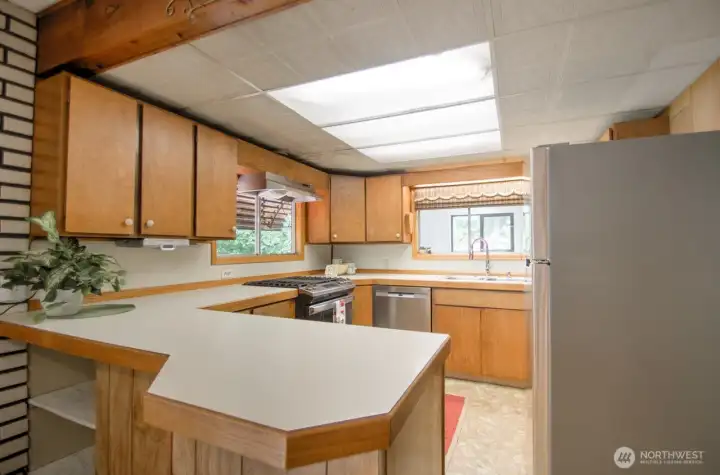 Kitchen offers lots of cabinet and counter space, with space to seat someone to keep the chef company.