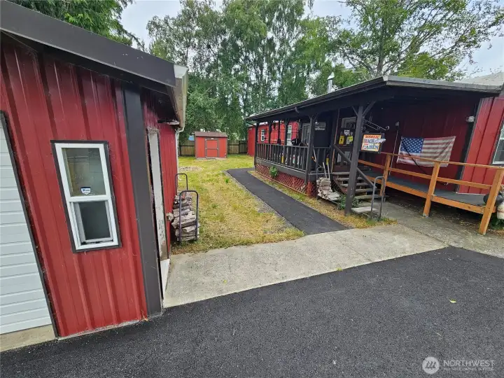 The front of the shop with a cement walkway to the house and a paved sidewalk around the covered deck.