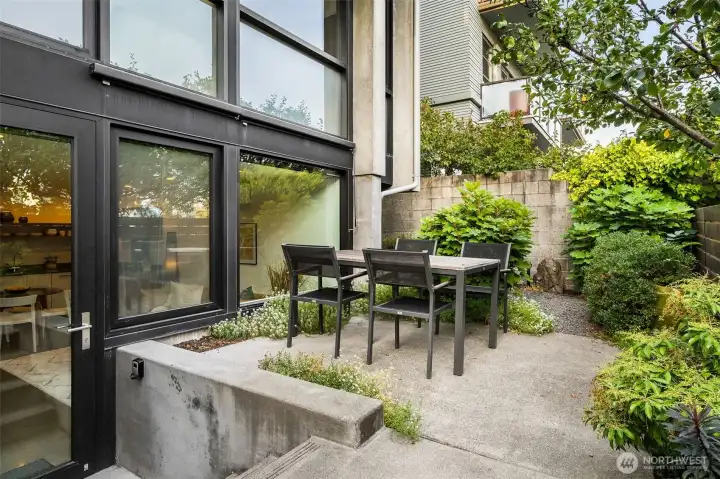Garden patio framed in lush greenery — a hidden pocket of calm just steps from city energy.