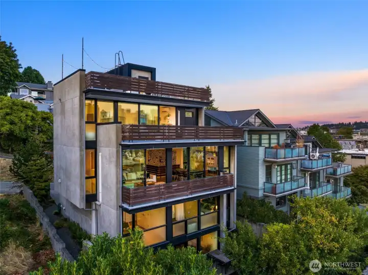 From the rear, the home reveals its drama — stacked glass walls and bold lines carving into the hillside.