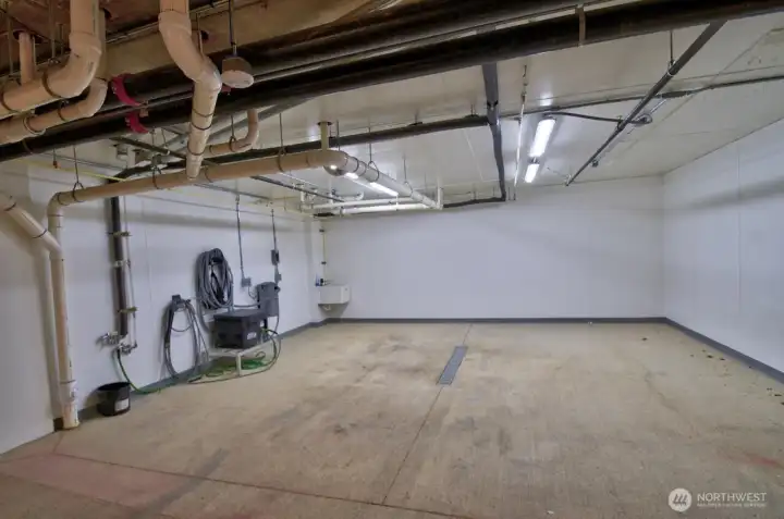 Car wash utility bay in garage includes a wall mounted vacuum.