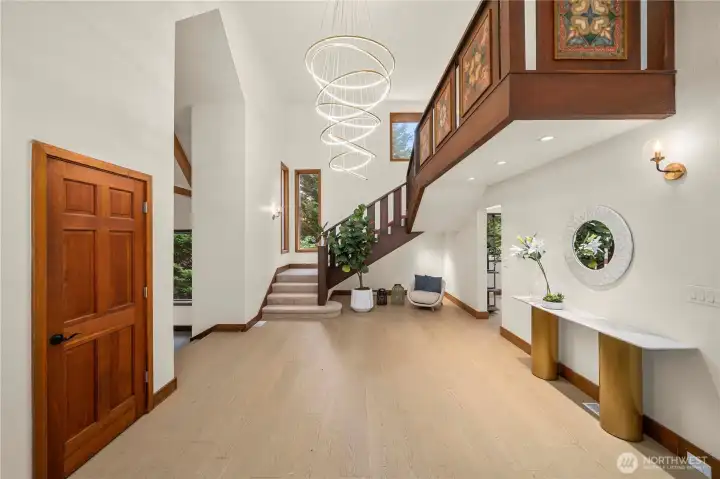 Grand entryway with soaring ceilings, beautiful lighting, and rich engineering hardwood floors sets the tone for refined living