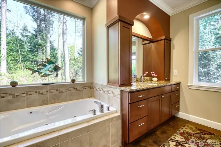 Gorgeous view of the backyard, from the jetted soaker tub. Beautiful cabinetry in the primary bathroom.